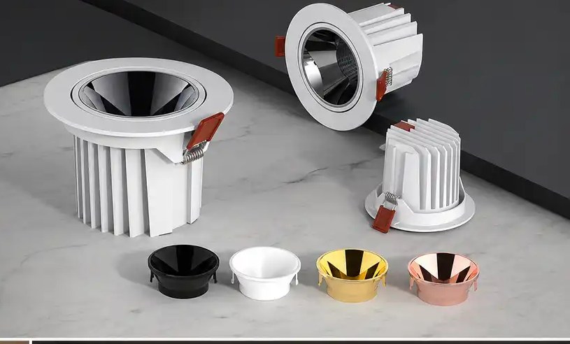Recessed COB LED downlights with finned heat sinks and spring clips, beside interchangeable reflector cups in black, white, gold and rose gold
